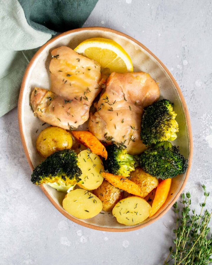 Overhead view of a plate with chicken things, broccoli, carrots, and potatoes with lemon.