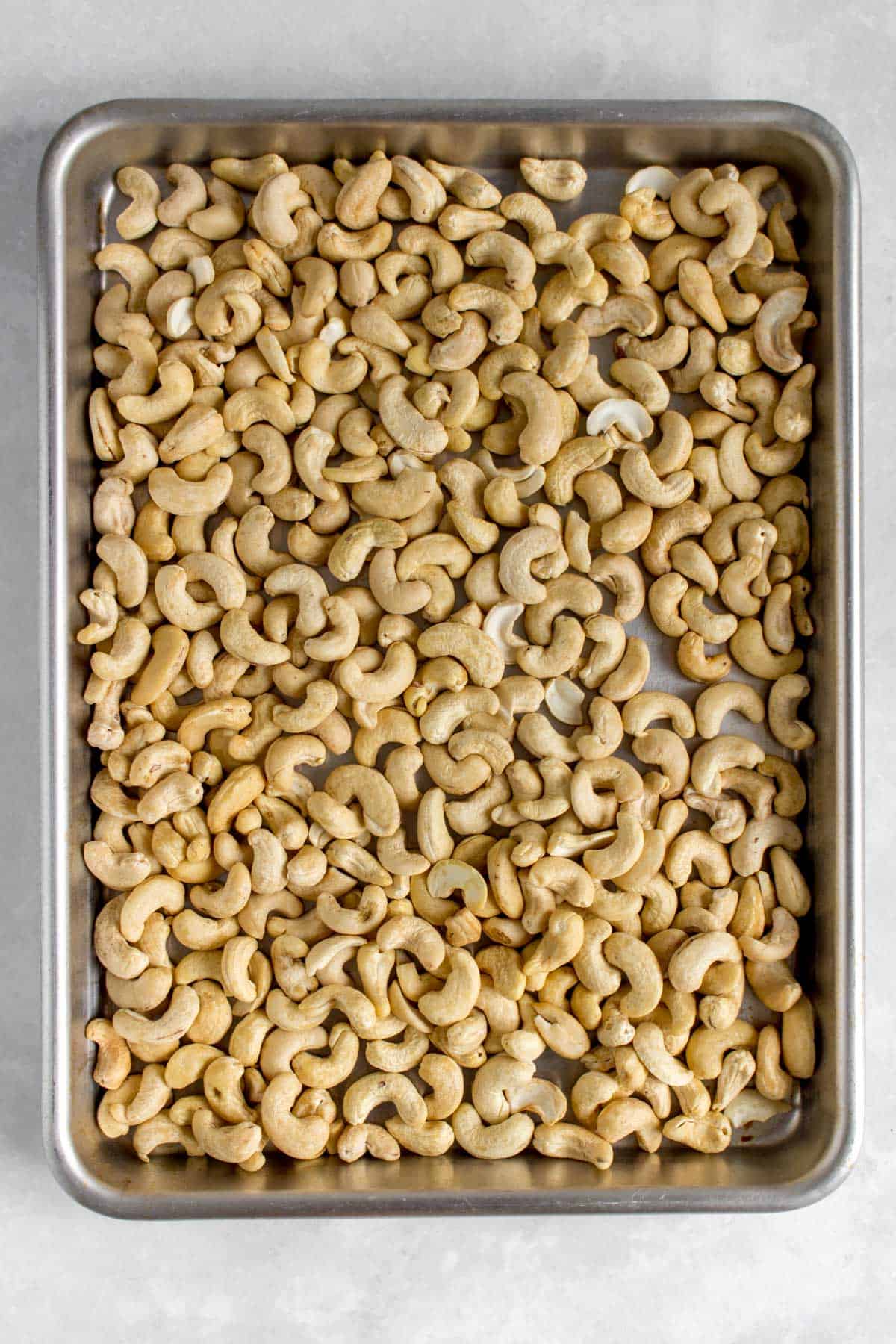 Sheet pan with raw cashews.