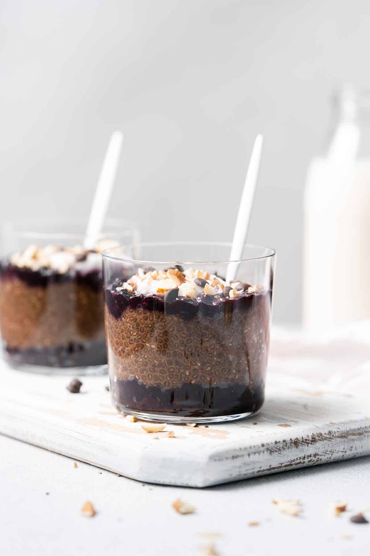 Two glasses of chocolate and blueberry chia pudding with one in the front, in focus.