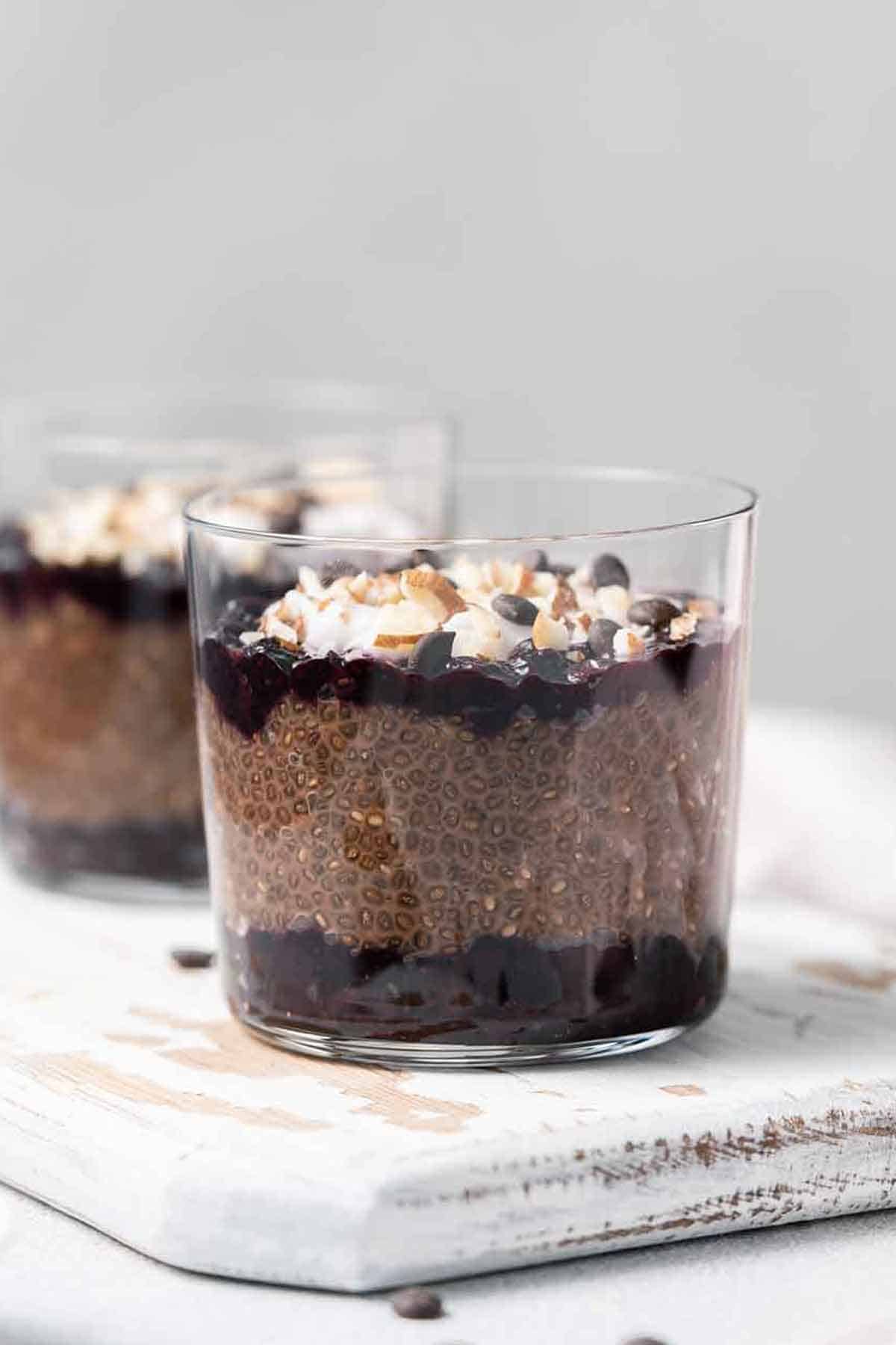 Two glasses of chocolate blueberry chia pudding with one in front and in focus.