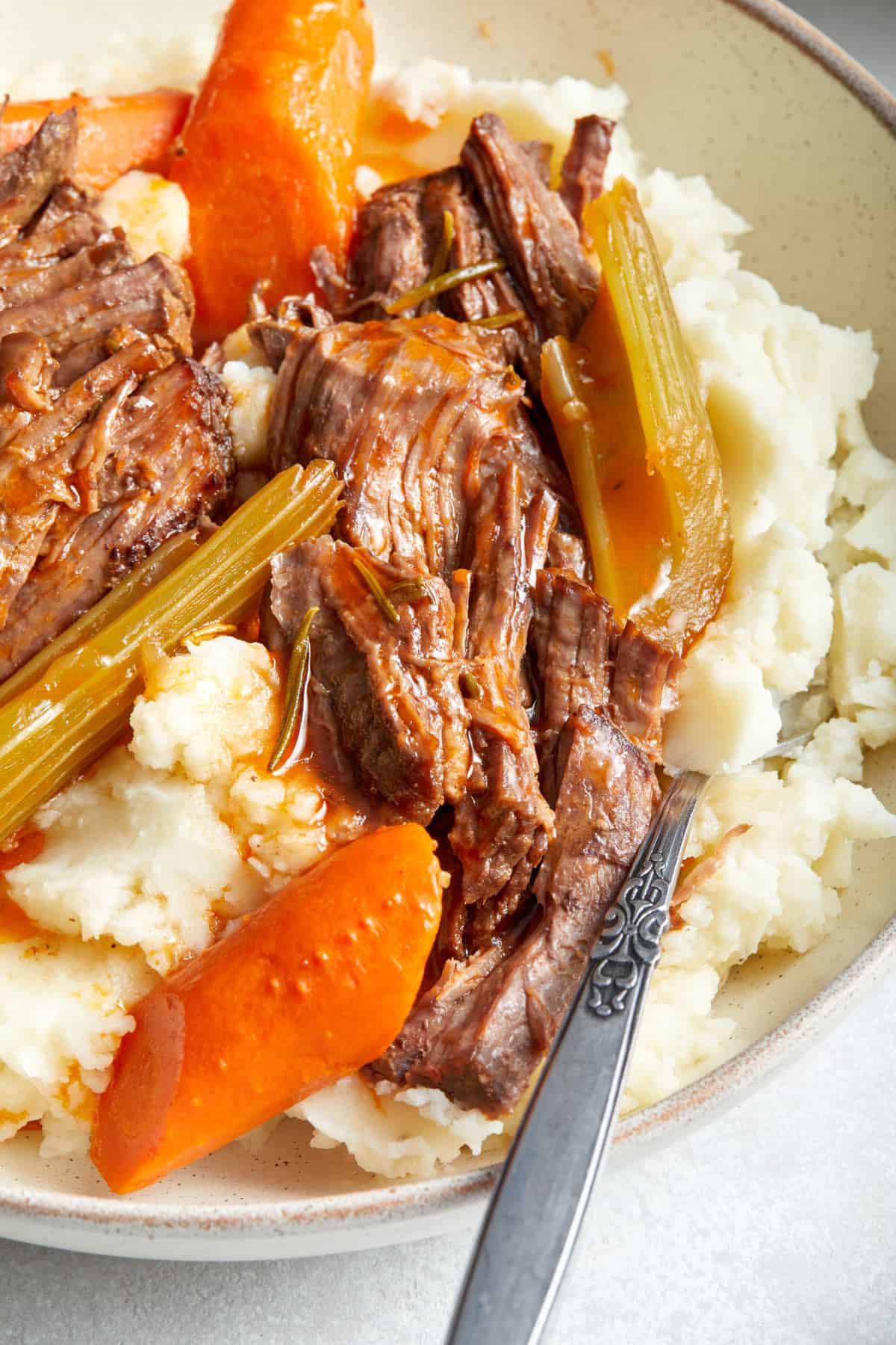 Close up of Dutch oven pot roast over mashed potatoes.