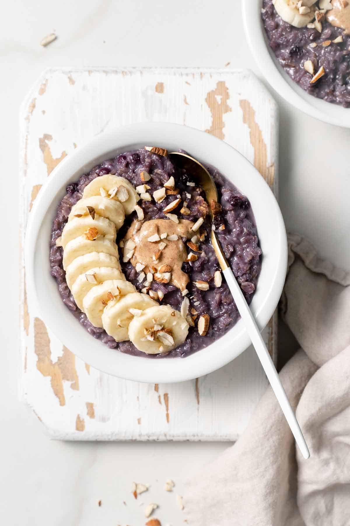 Overhead view of a bowl of blueberry oats with a dollop of nut butter and sliced bananas on top.
