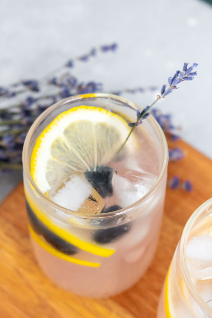 Slightly overhead view of a glass of blueberry lavender lemonade with lavender garnish.