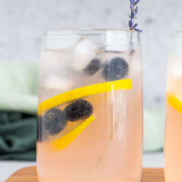 A glass of blueberry lavender lemonade with a piece of lavender garnished on top.