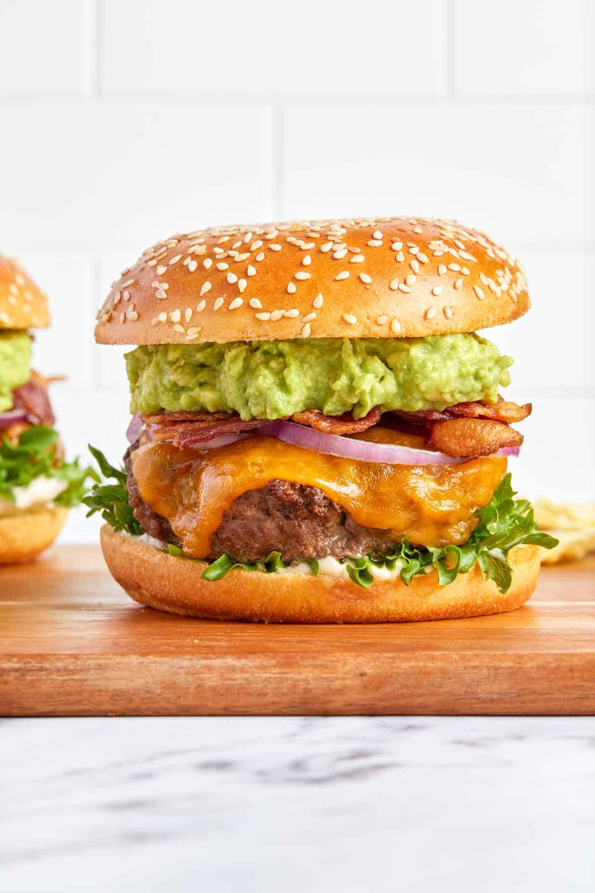 Profile view of an avocado burger on a cutting board.