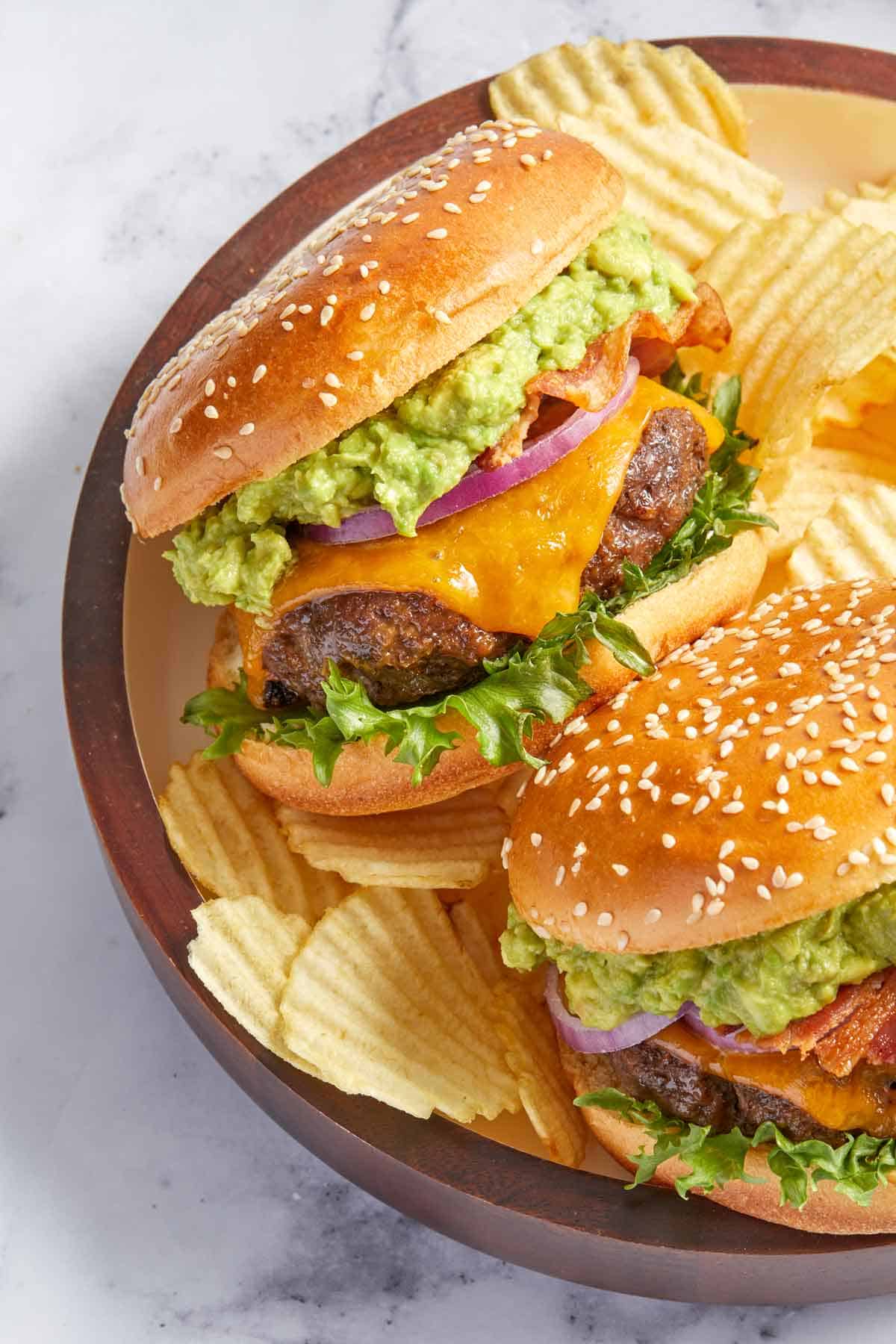 A plate with two avocado burgers over ruffled chips.