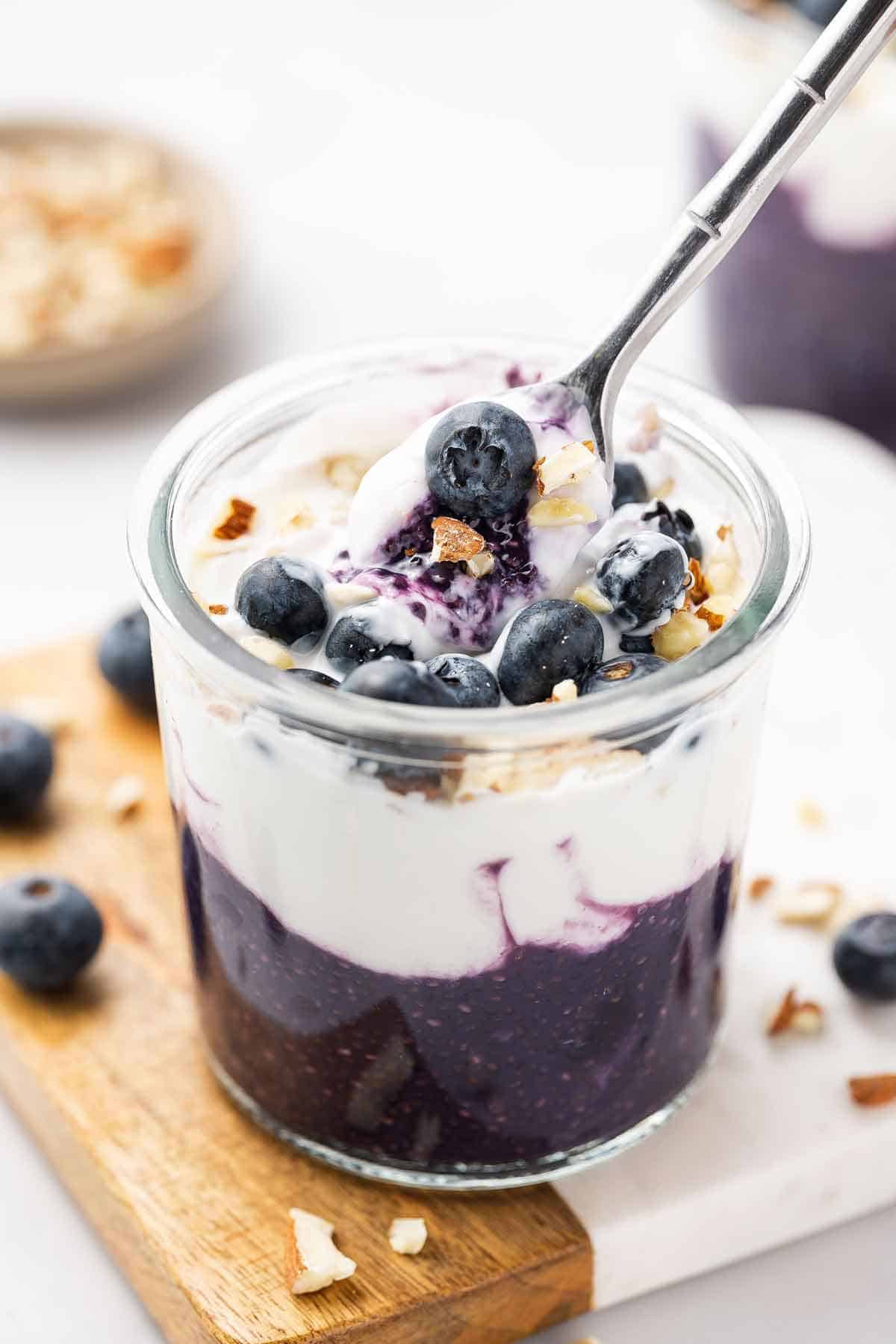 A spoonful of blueberry chia pudding lifted from the glass.