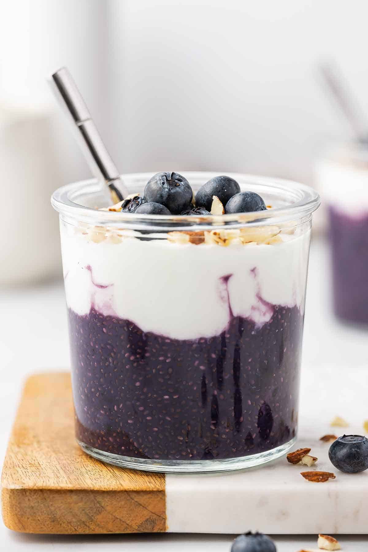 A jar of blueberry chia pudding with a layer of yogurt on top with blueberries and sliced almonds.