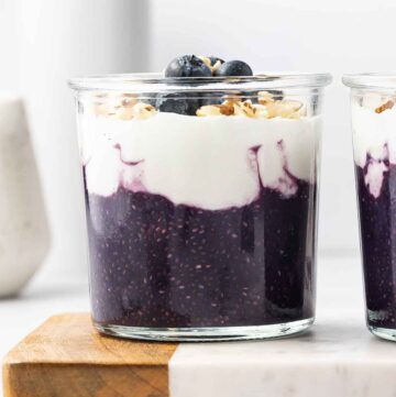 A glass of blueberry chia pudding topped with yogurt and blueberries.