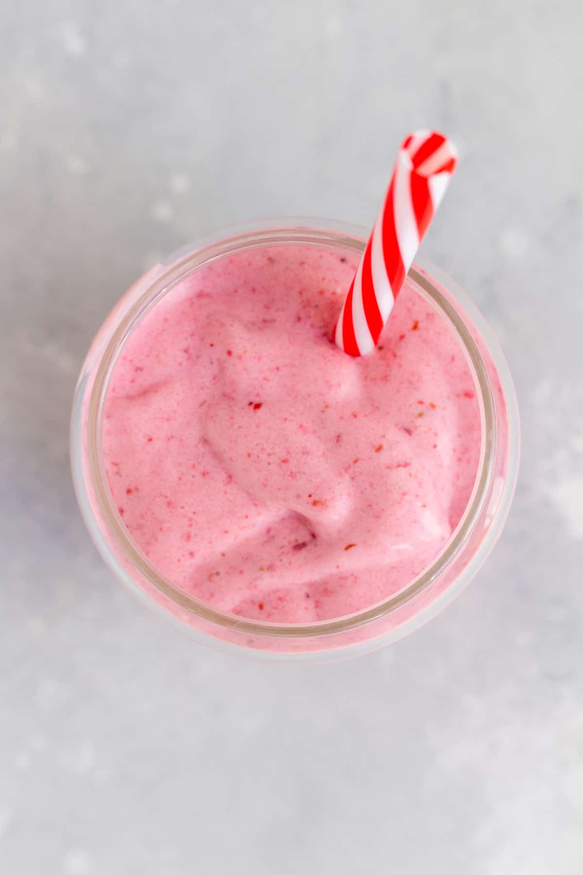 Overhead view of a glass of frozen fruit smoothie with a straw inside.
