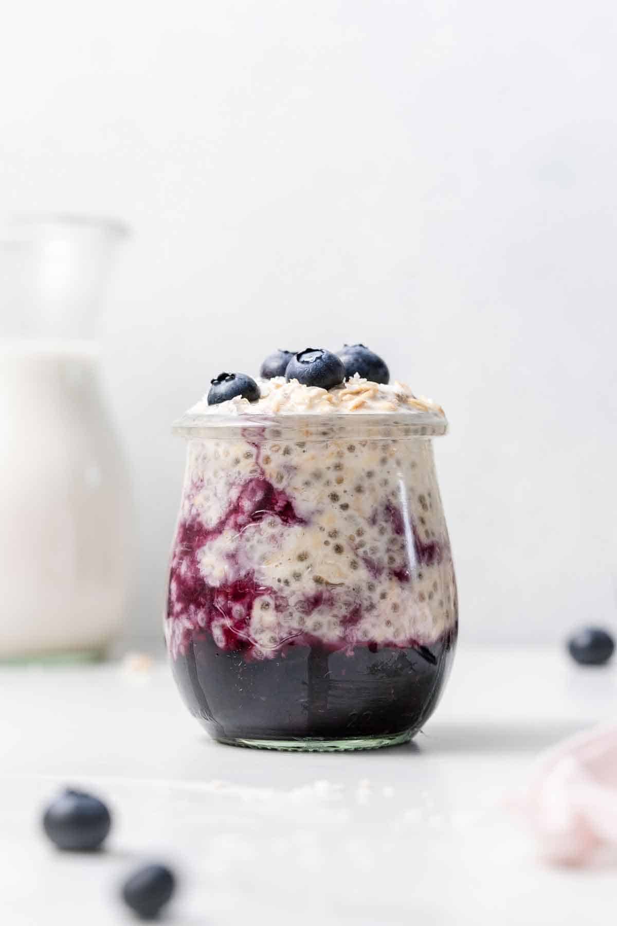 A jar of blueberry overnight oats with blueberries and coconut on top.