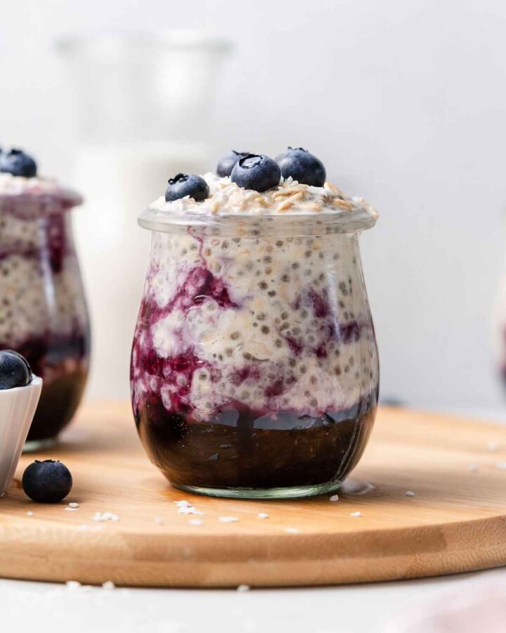 A jar of blueberry overnight oats on a serving board.
