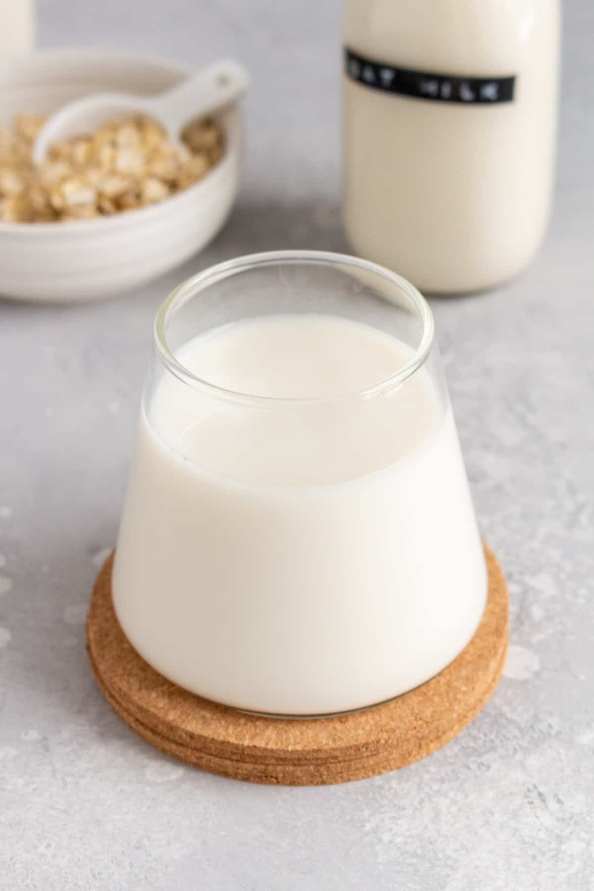 A glass of oat milk on cork coaster.
