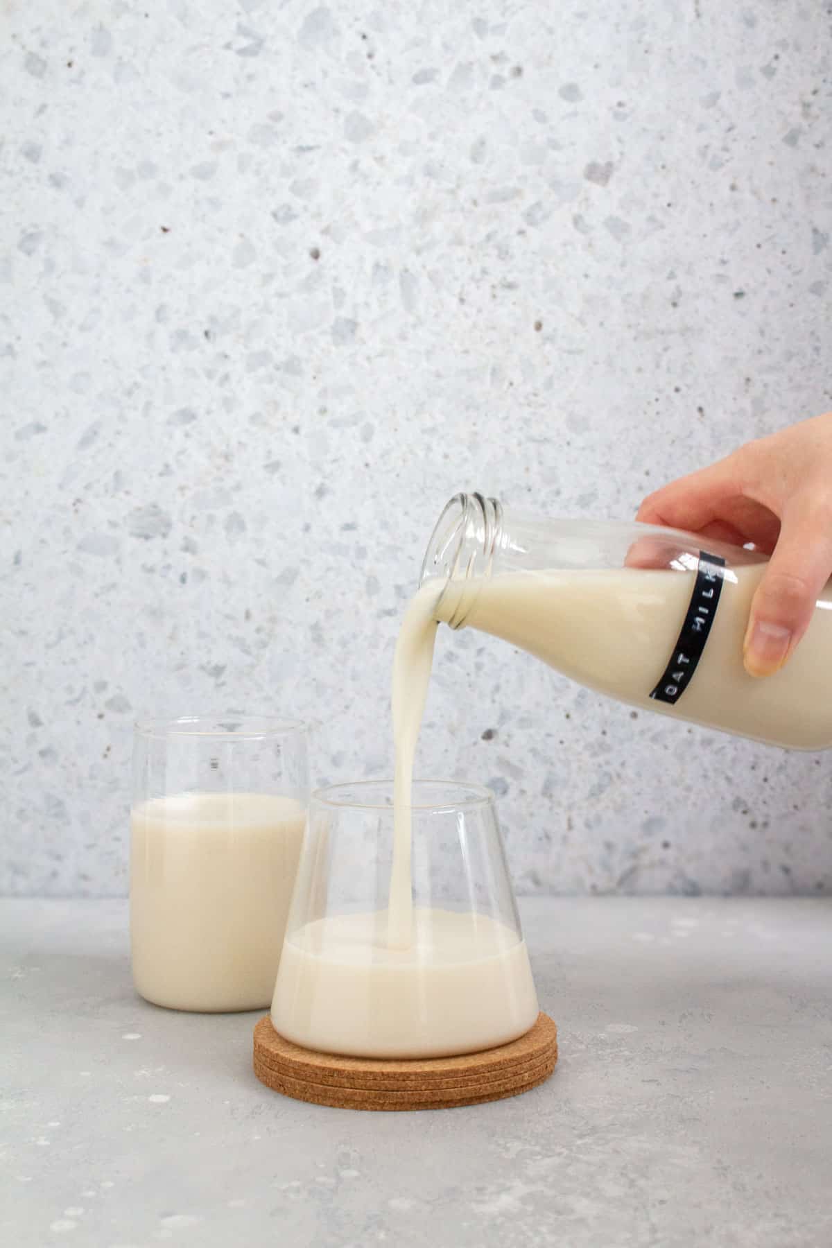 A bottle of oat milk poured into a glass.