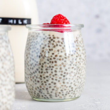 A jar of oat milk chia pudding with fresh raspberries on top.