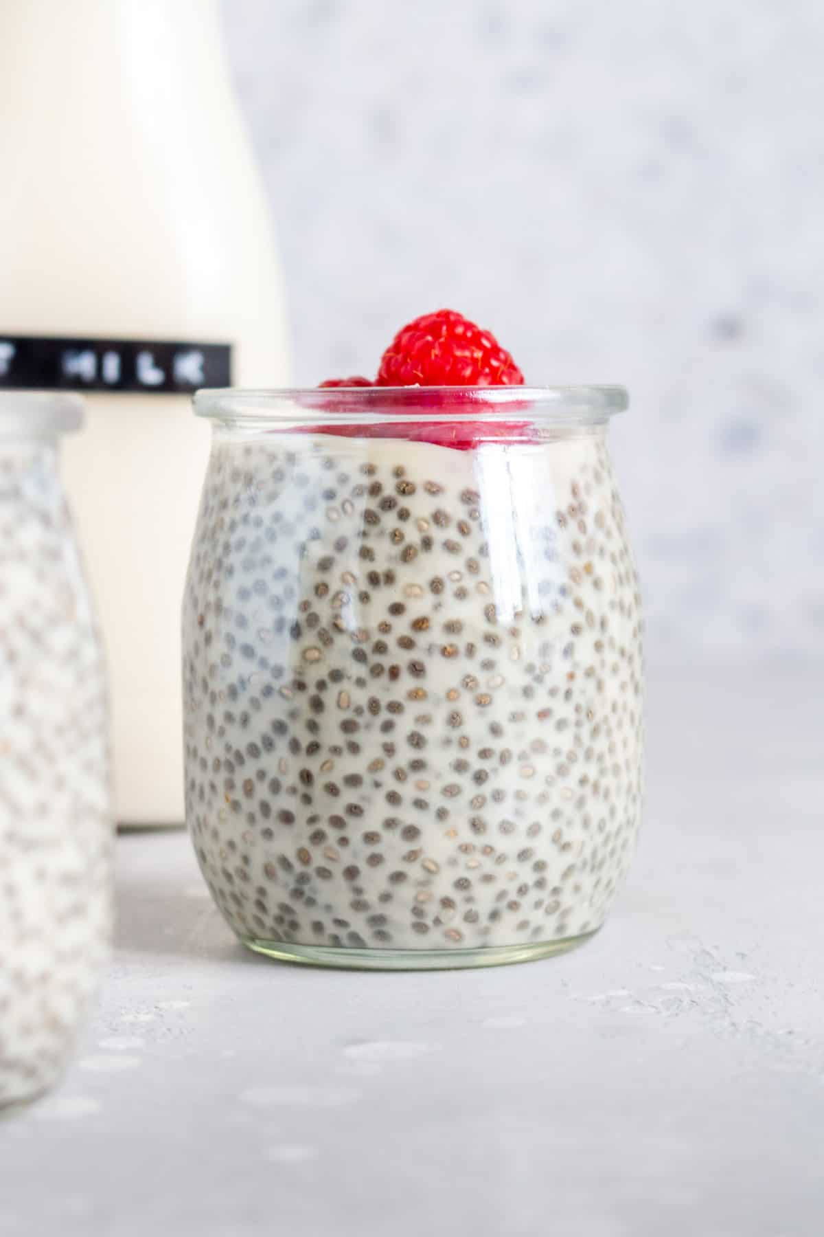 A jar of oat milk chia pudding with fresh raspberries on top.