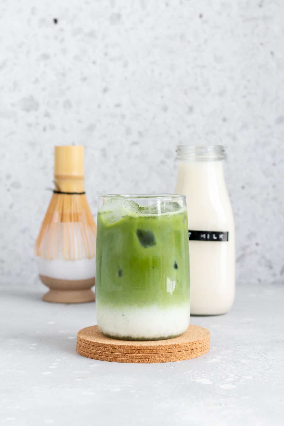 A glass of oat milk matcha latte with the matcha and milk separated.
