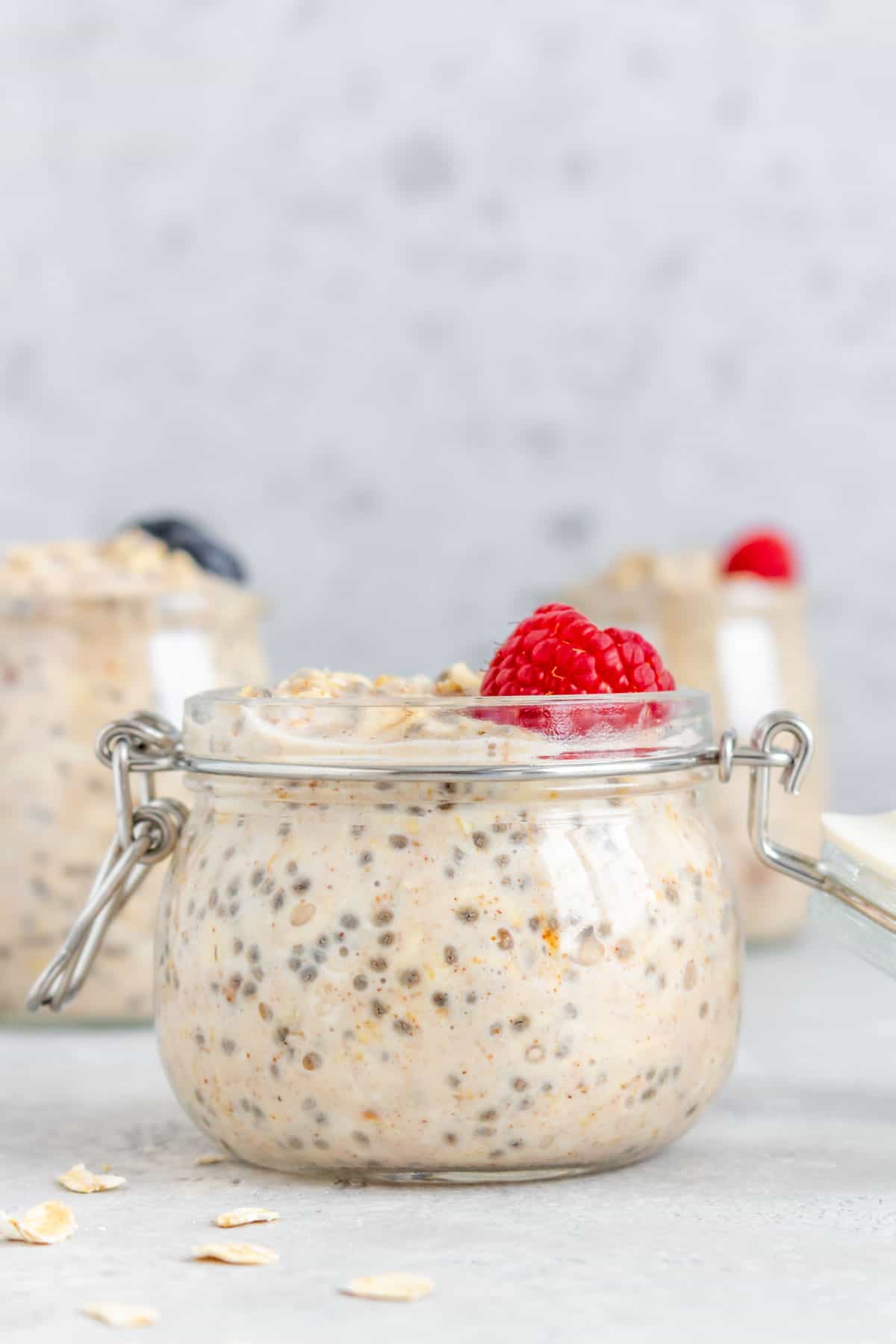 A jar of overnight oats with almond milk with a raspberry on top.