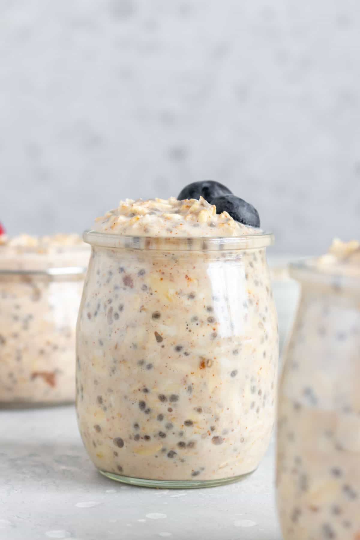 A jar of almond milk overnight oats topped with two blueberries.