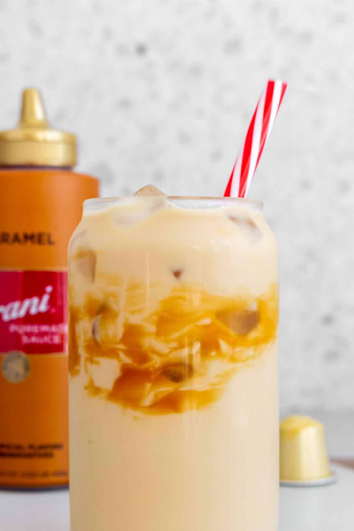 Close up of a glass of caramel macchiato with a striped straw.