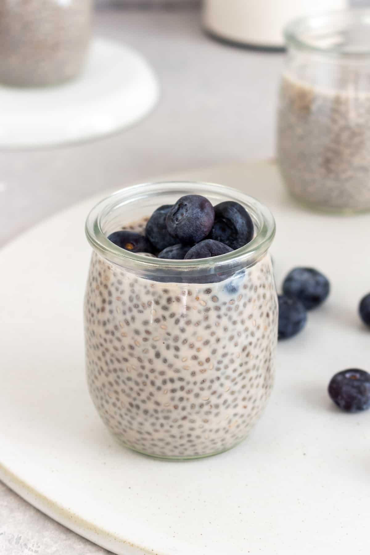 A cup of protein chia pudding with fresh blueberries on top.