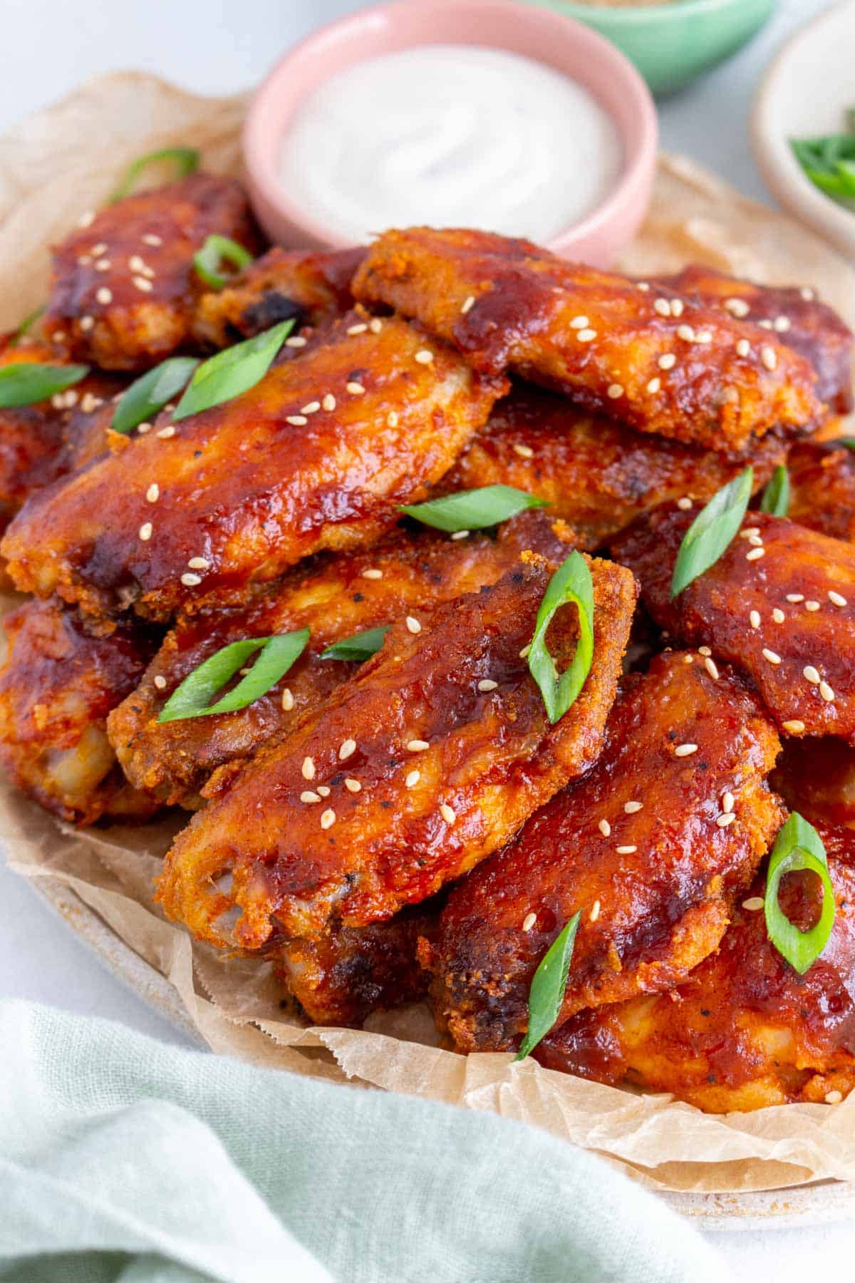 Close up view of crispy bbq chicken wings with sesame seeds and green onions on top.
