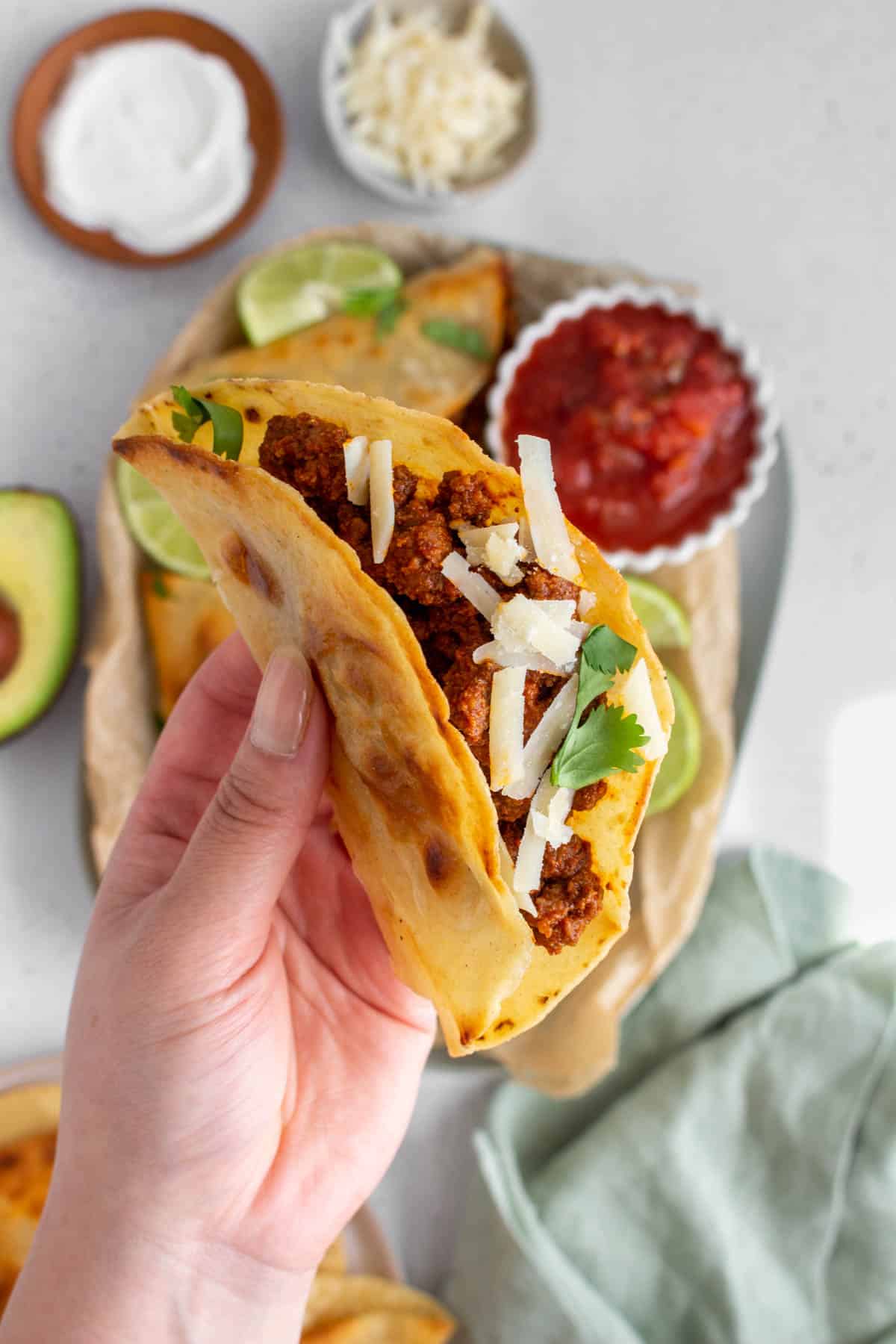 A hand holding up a ground beef taco.