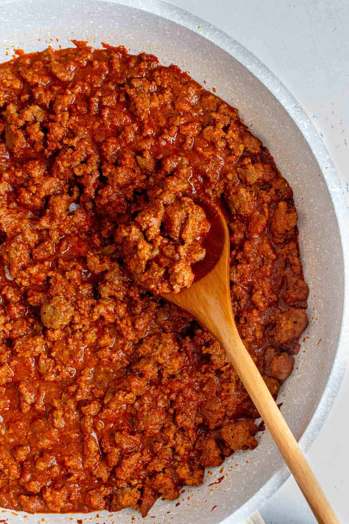 Overhead view of taco meat in a skillet with a wooden spoon.