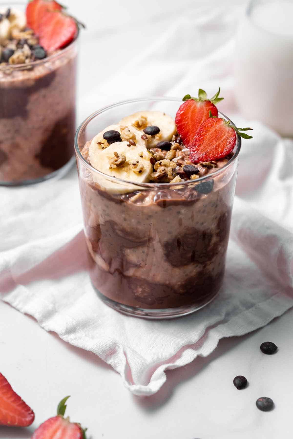 A jar of nutella overnight oats with cut strawberries, bananas, chocolate chips, and granola.