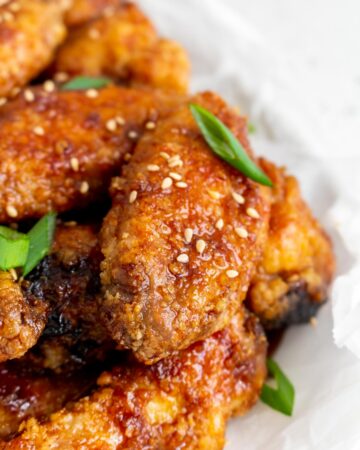 Close up view of soy garlic chicken wings with sesame seeds and green onions.