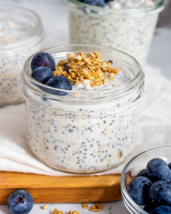 A jar of vanilla overnight oats with granola and blueberries on top.