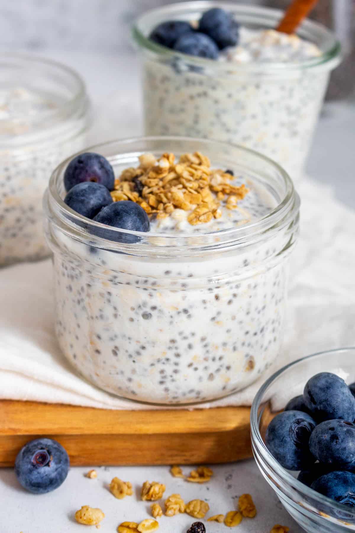 A jar of vanilla overnight oats with granola and blueberries on top.