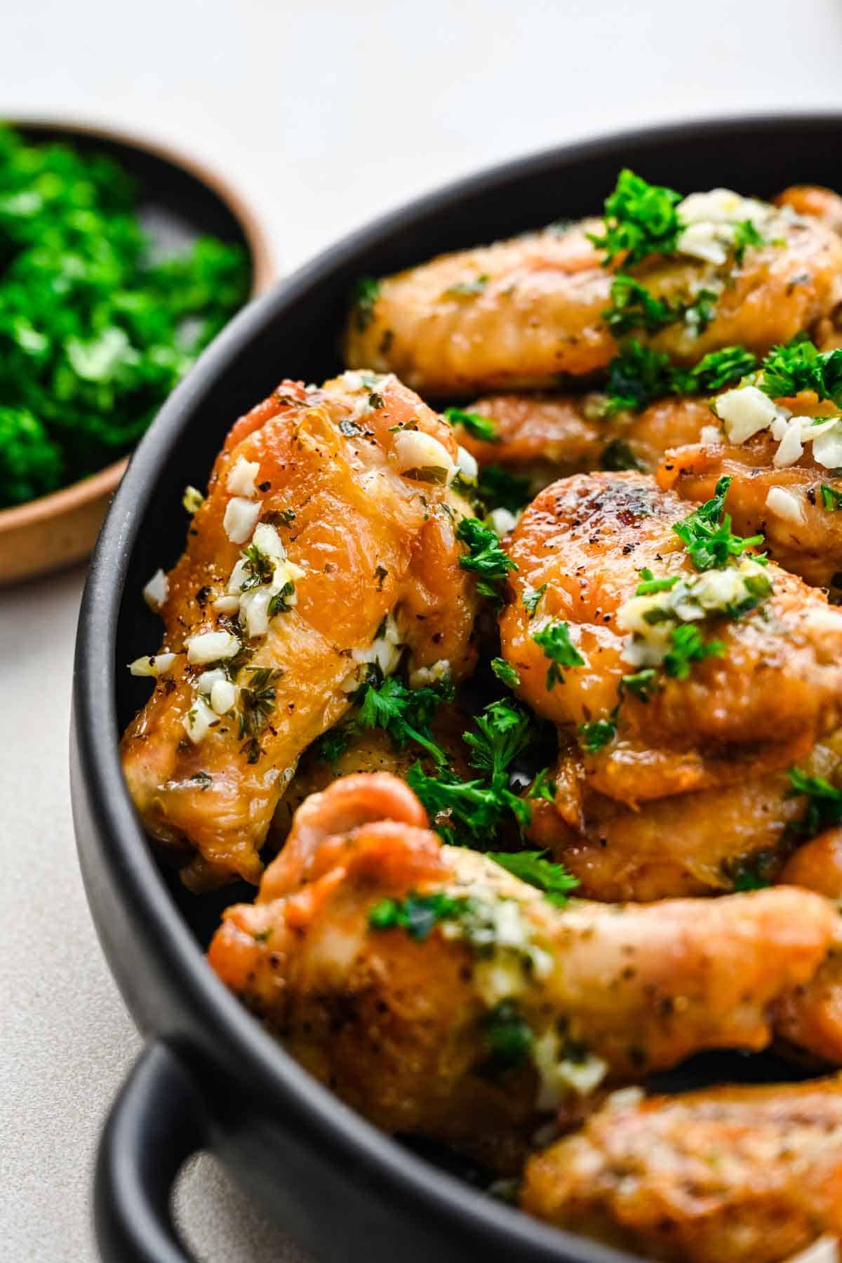 Close up of garlic butter chicken wings in a bowl.
