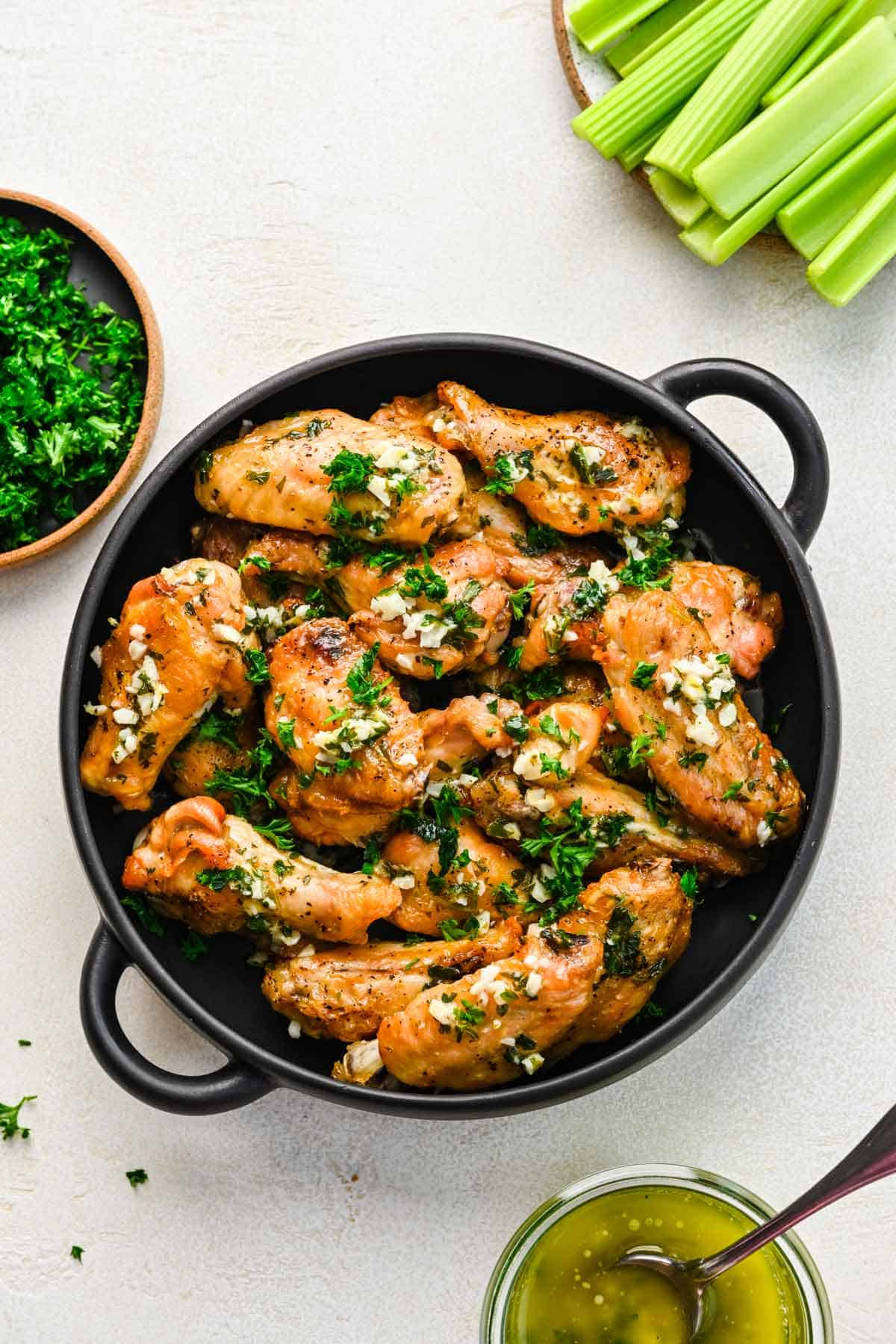 Overhead view of garlic butter chicken wings topped with minced garlic and chopped parsley.