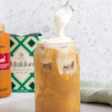 A spoonful of salted caramel cold foam added to a coffee.