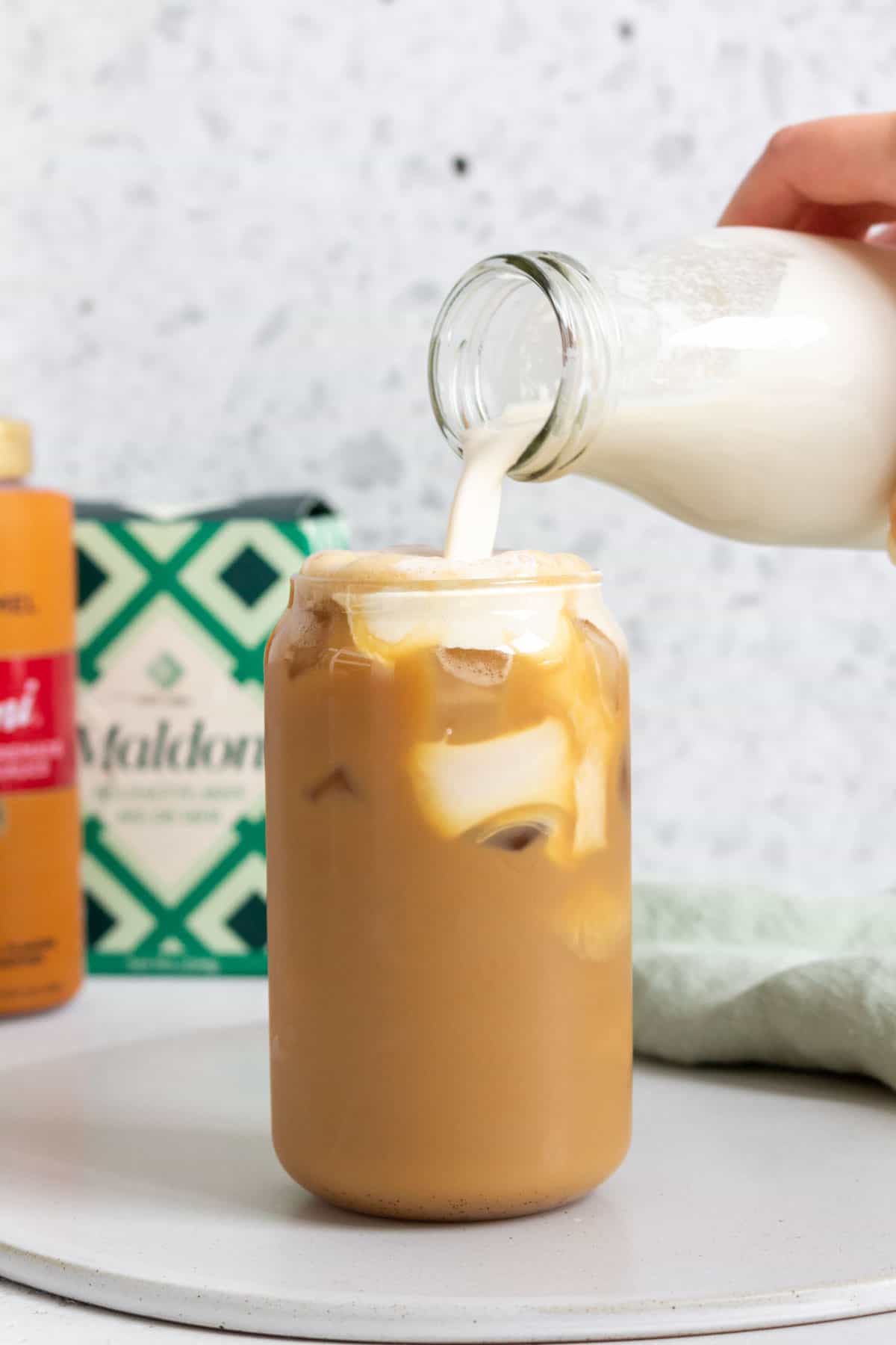 A glass of salted caramel cold foam poured into an iced coffee.