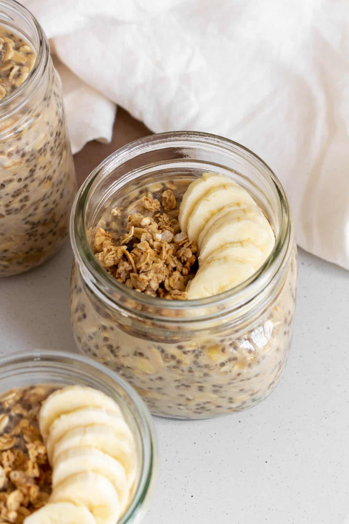 Angled photo of a jar of brown sugar overnight oats with sliced bananas and granola on top.