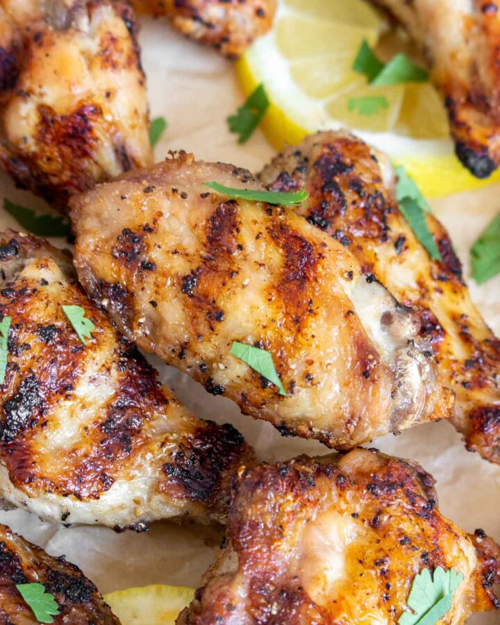 A close up view of grilled chicken wings with grill marks garnished with cilantro.