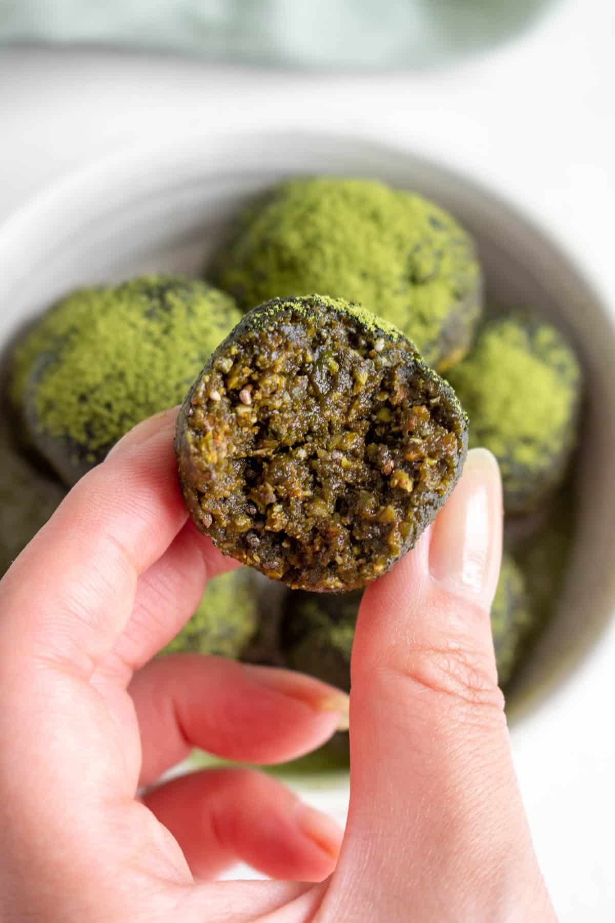 A hand holding up a matcha ball with a bite taken out.