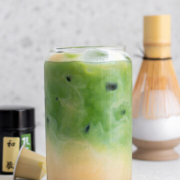 A glass of matcha espresso with the espresso layer on the bottom and matcha layer on top.