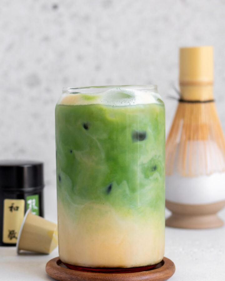 A glass of matcha espresso with the espresso layer on the bottom and matcha layer on top.