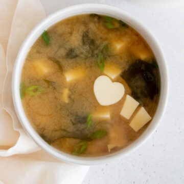 Overhead view of a bowl of miso sauce with a heart shaped piece of tofu.