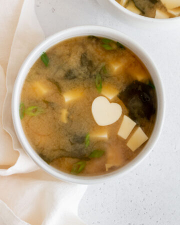 Overhead view of a bowl of miso sauce with a heart shaped piece of tofu.