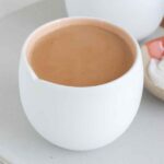 A mug of royal milk tea with sugar in the back.