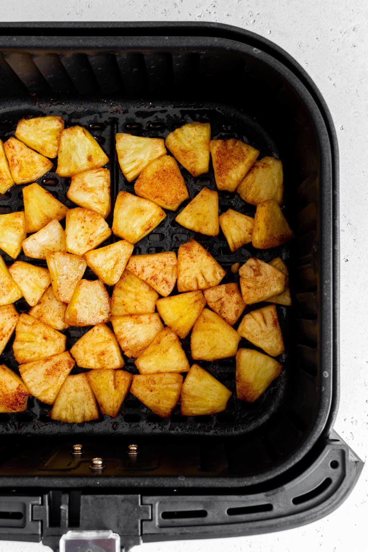 An air fryer basket with air fryer pineapples.