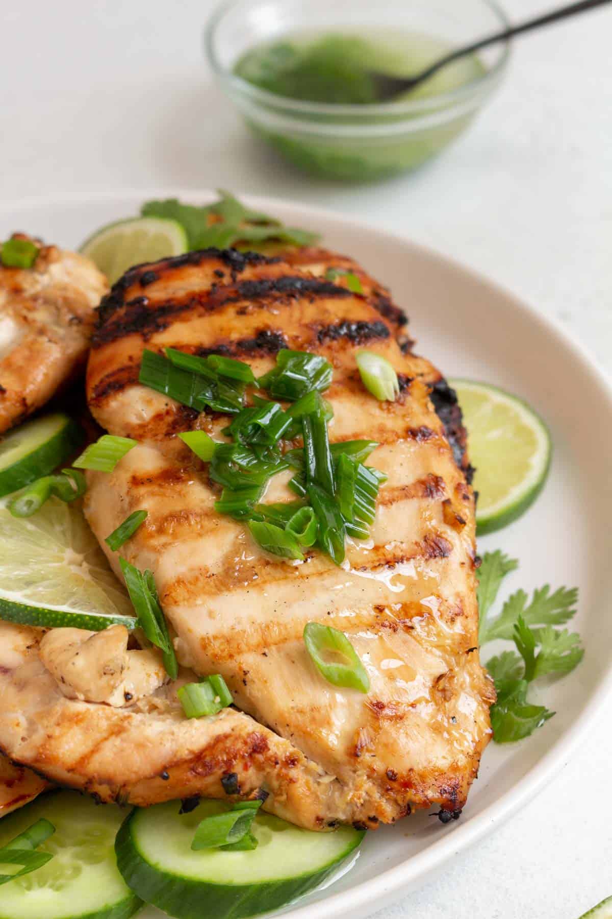 A close up view of a grilled lemongrass chicken breast with scallion oil on top.