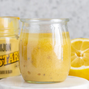 A jar of lemon honey dijon vinaigrette on a marble coaster.