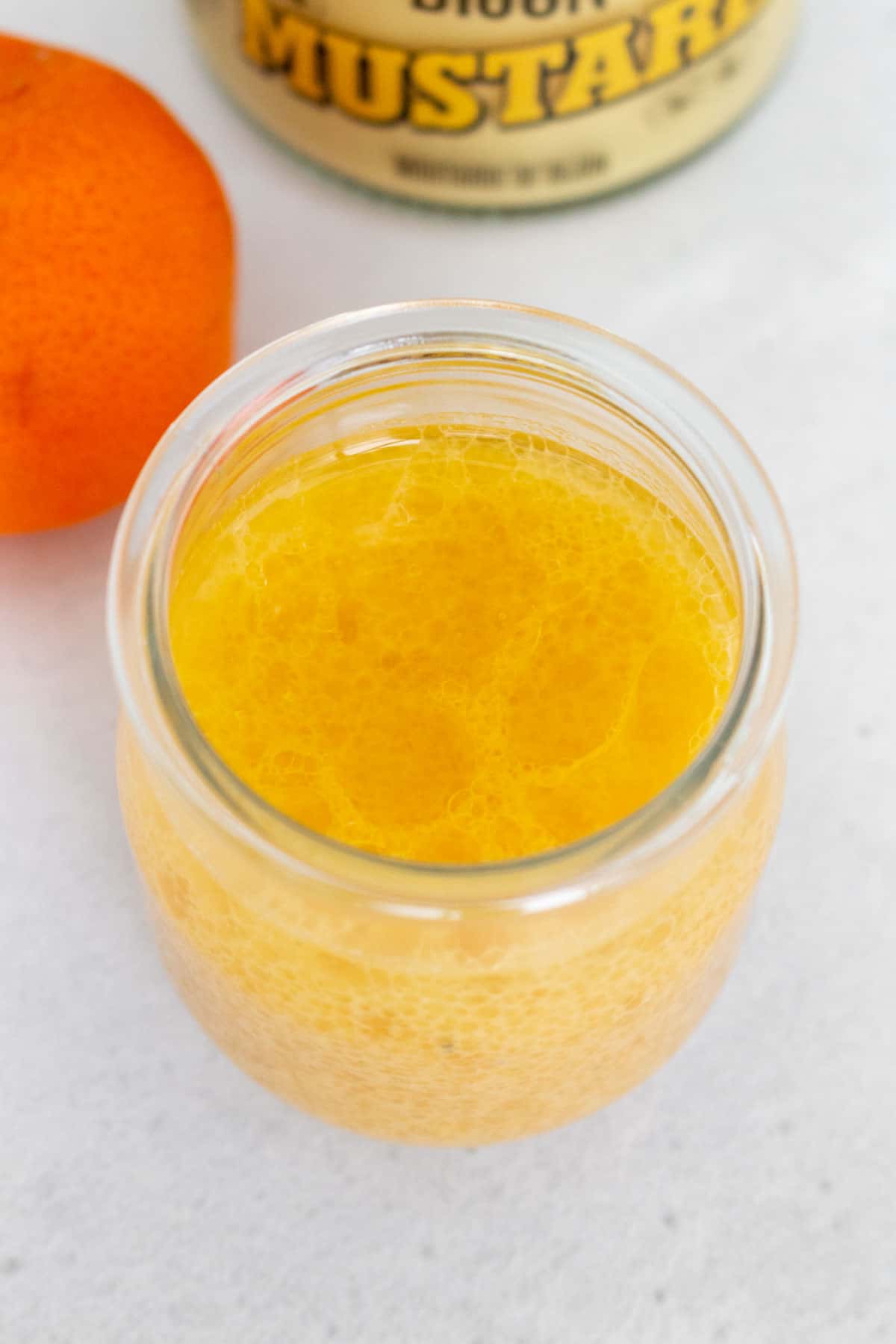 Angled view of a jar of orange mustard dressing.