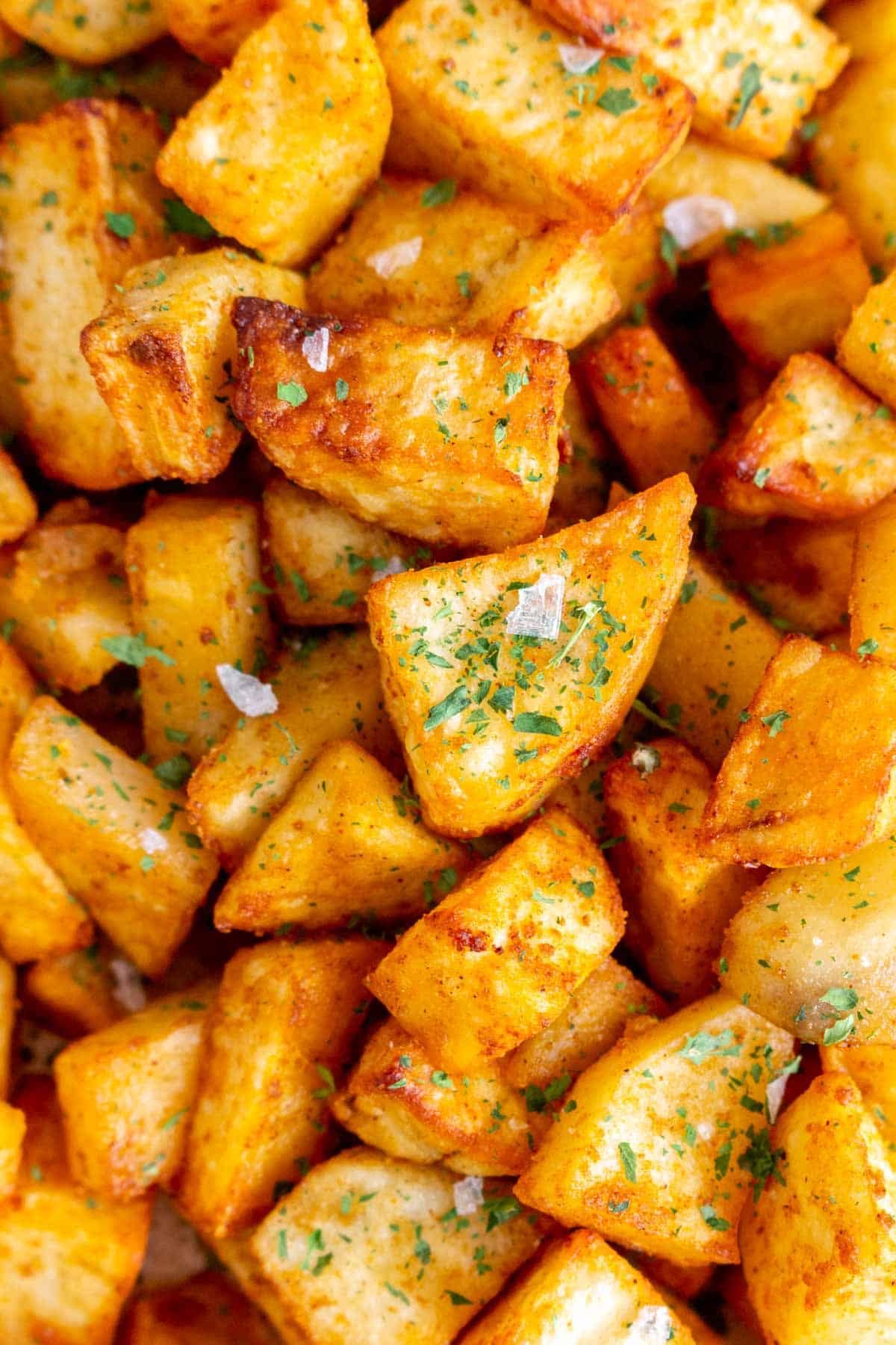 A close view of air fryer breakfast potatoes with parsley and salt flakes.