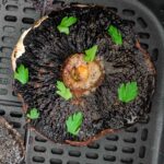 Overhead view of an air fryer portobello mushroom in the basket with parsley on top.